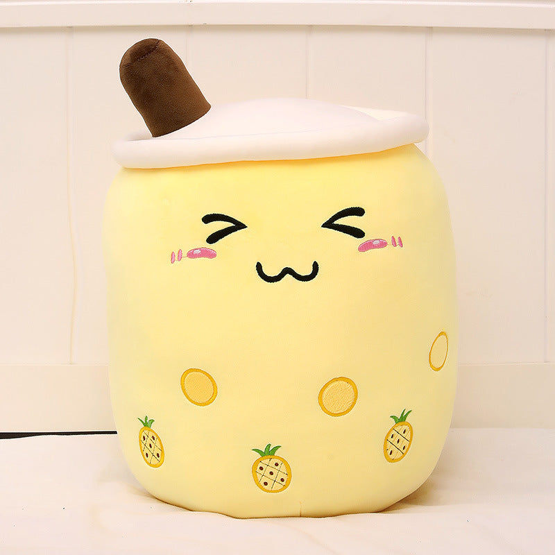Yellow plush bubble tea cup pillow with brown straw, smiling face and pineapple icons