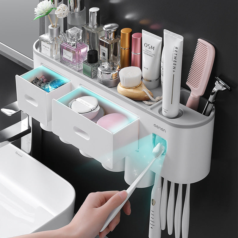 White toothbrush holder with open drawer and slots holding toothbrushes and accessories