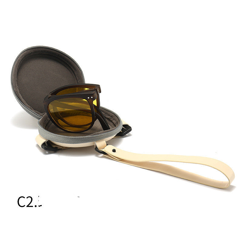 Foldable sunglasses with amber-brown frames and dark lenses, shown with hard case