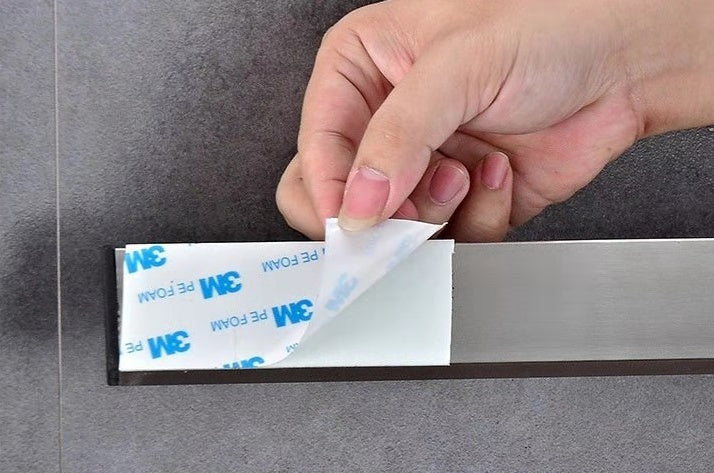 Hand pressing a paper strip onto a stainless magnetic knife holder bar