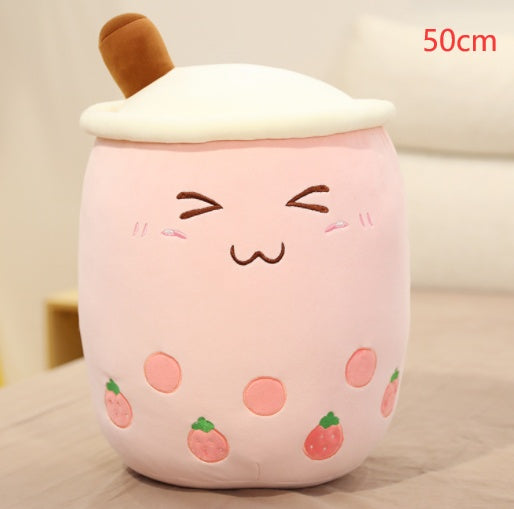 Light pink plush boba drink pillow with closed-eye face, white lid and tan straw