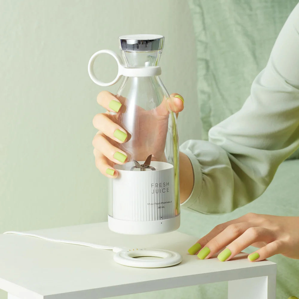 Portable mini fruit blender with clear bottle, white base, and loop handle cup