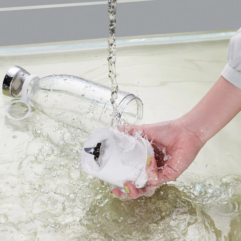 Portable mini fruit blender base being rinsed under running water