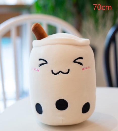 White plush boba tea cup pillow with brown straw, smiling face, and black dot details
