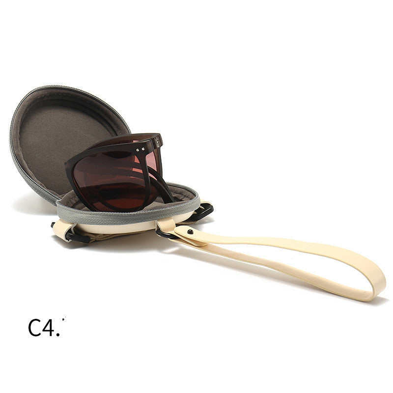 Foldable sunglasses with light beige frames and dark lenses, shown with hard case