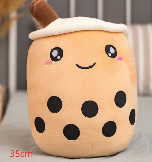 Tan plush boba drink cup pillow with brown straw, white top, cute face and dark bubble spots
