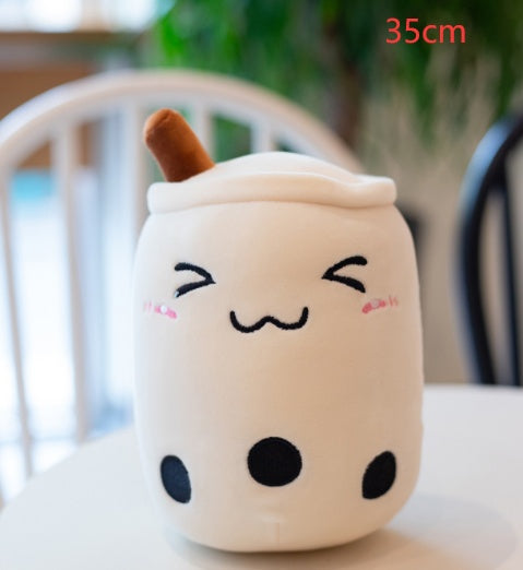 Cream plush bubble tea cup pillow with brown straw, sleepy face and black dot details