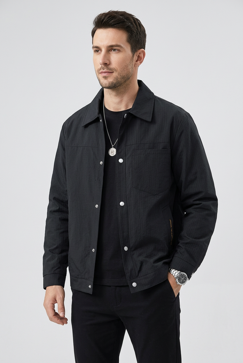 Slim male model wearing REEVEAR black snap-down jacket, three-quarter view