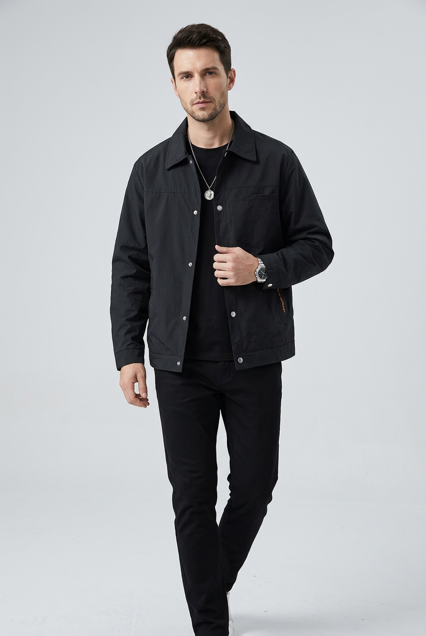 Slim male model wearing REEVEAR black snap-down jacket, walking pose